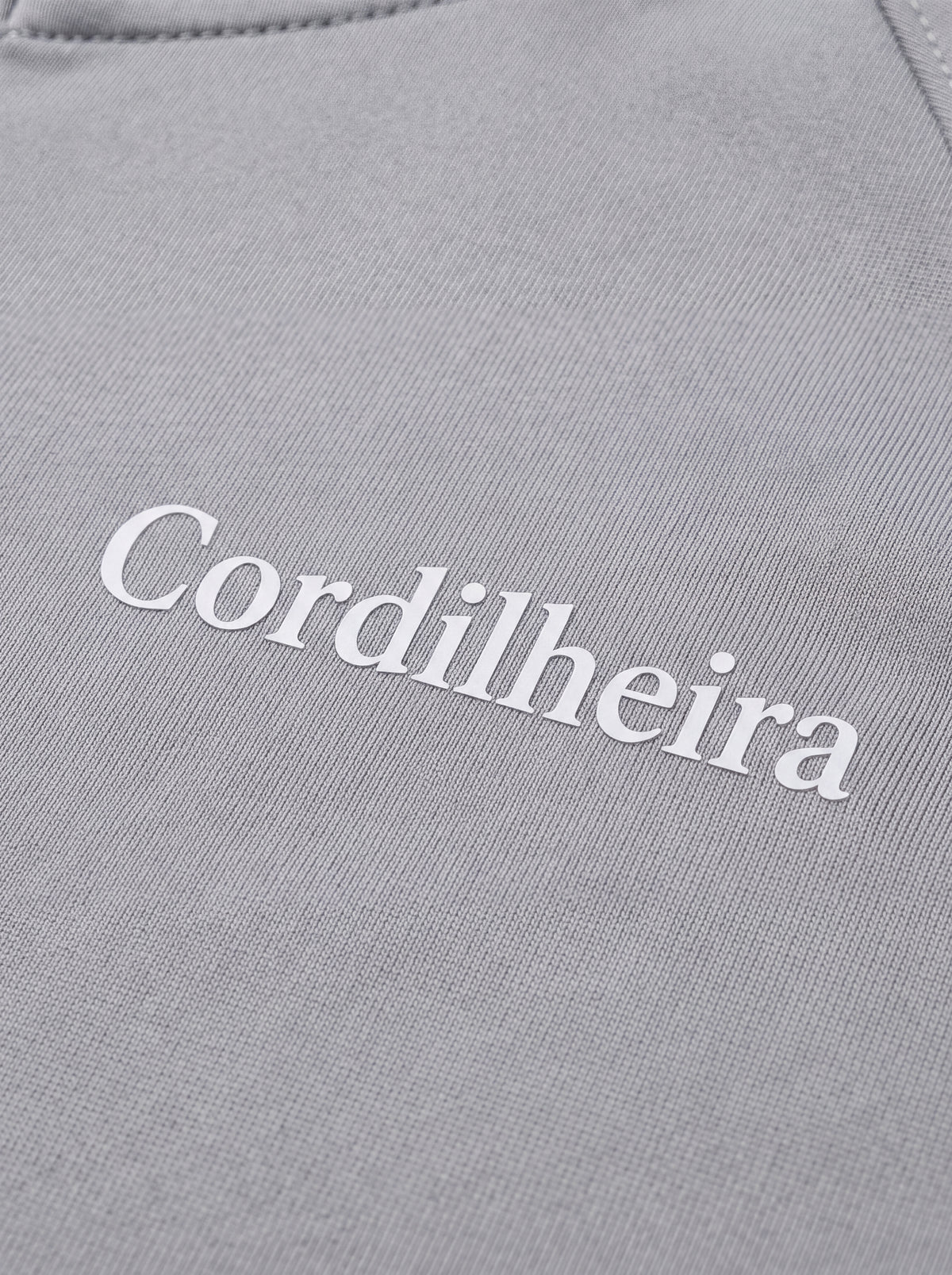 Close-up do tecido e logo da Roupa Corta-Vento Cordilheira Solar UV50+ Feminina da Marca Cordilheira, destacando Boa qualidade, resistência e acabamento Confiável para uso esportivo.