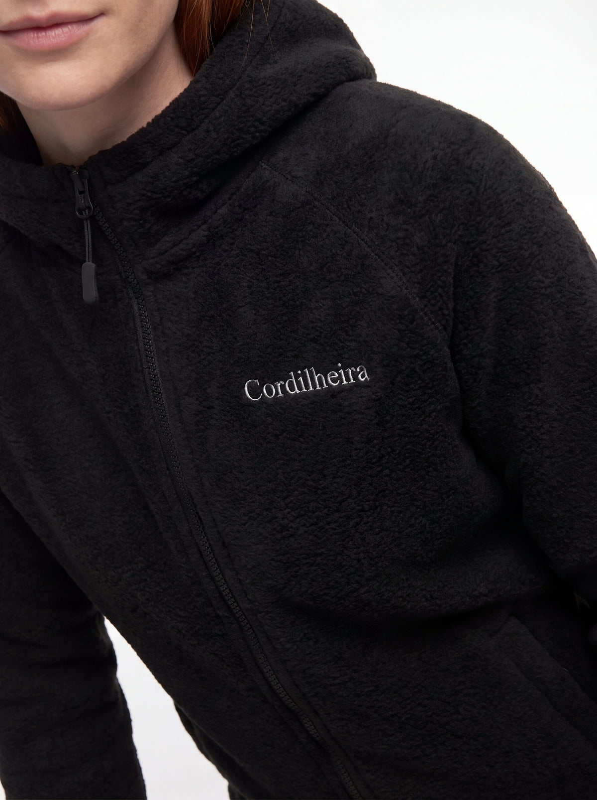 Modelo mostrando o logo bordado da Jaqueta Cordilheira Fleece Hooded Feminina, Roupa da Marca Cordilheira com Boa qualidade, resistência e acabamento Confiável.