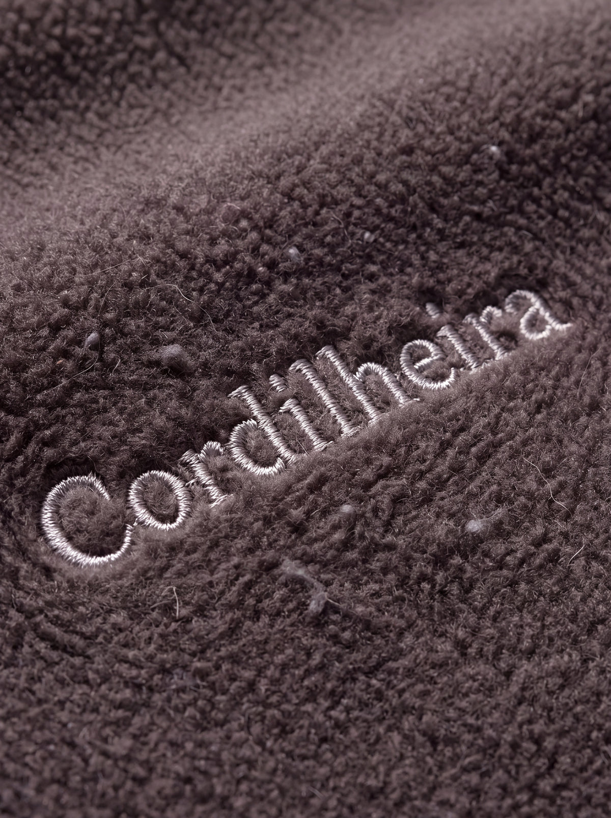 Close-up do logotipo bordado no fleece interno da Jaqueta 3 em 1 Cordilheira Alpine Feminina, Roupa da Marca Cordilheira com Boa qualidade, resistência e acabamento Confiável para frio e esportes de inverno.