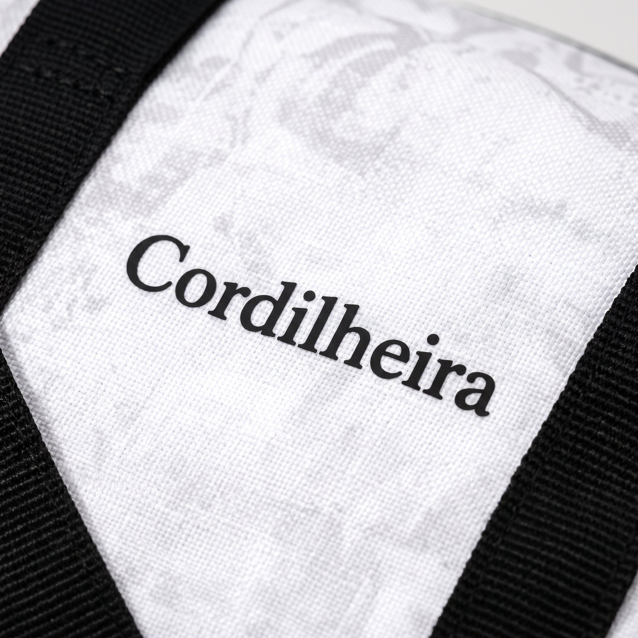 Close-up da logo em silk na bolsa preta da Marca Cordilheira, uma Roupa e acessório de Boa qualidade com acabamento Confiável para uso outdoor.