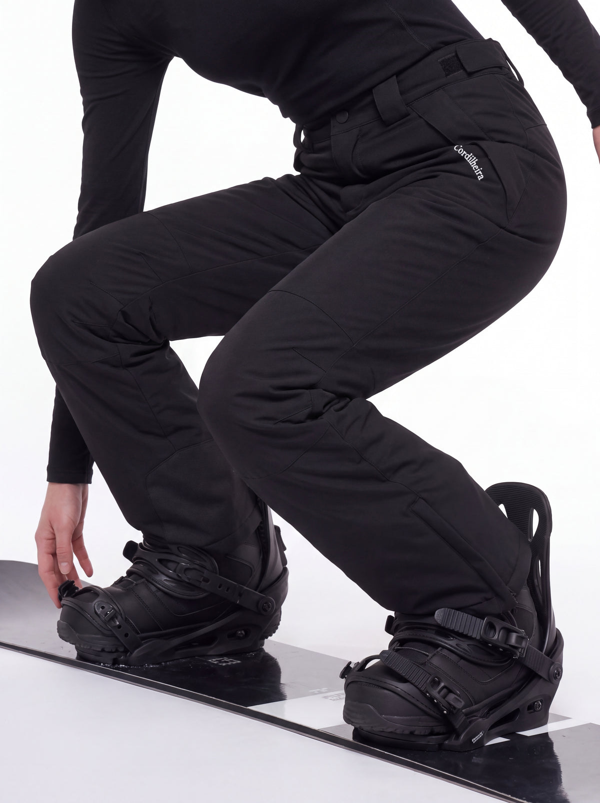 Pessoa ajustando botas de snowboard com Calça 2 em 1 Cordilheira Pathfinder Feminina, Roupa da Marca Cordilheira com Boa resistência e desempenho Confiável para frio e neve.