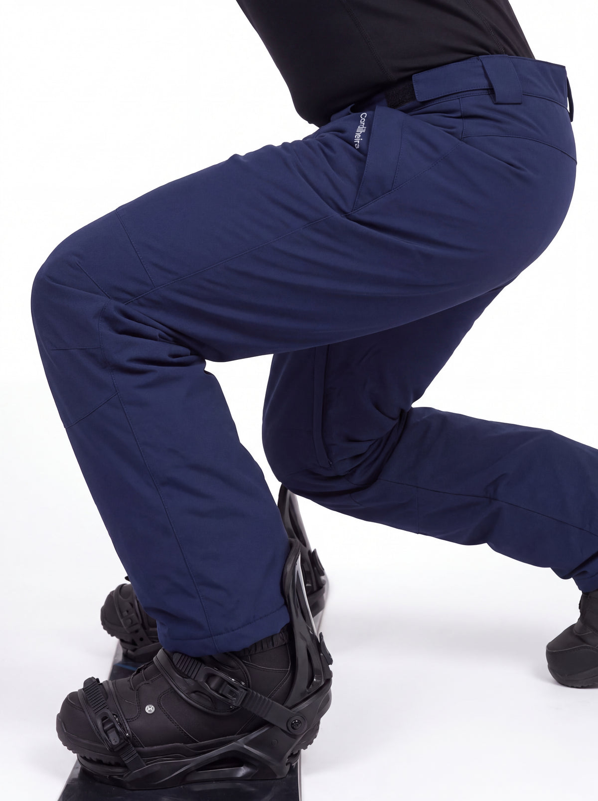 Praticante ajustando as botas com Calça 2 em 1 Cordilheira Pathfinder Masculina, Roupa da Marca Cordilheira com Boa resistência e uso Confiável para snowboard e neve.