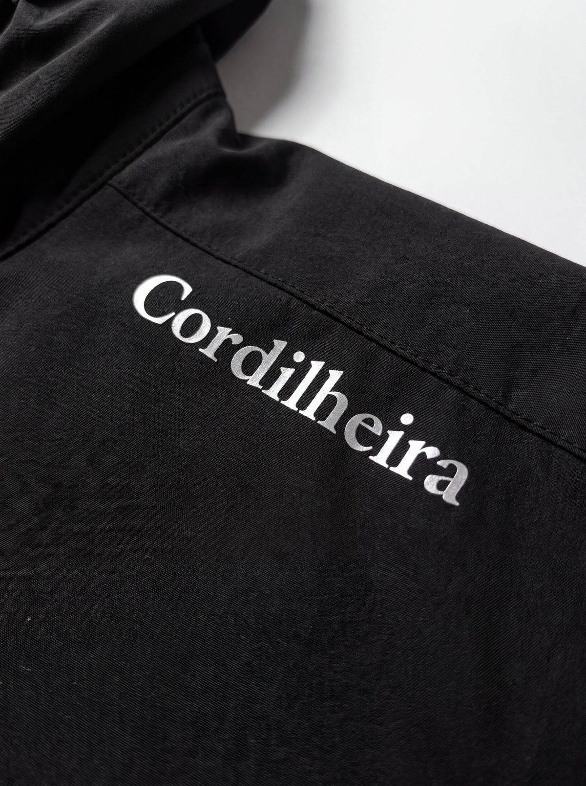 Zoom macro no logotipo do Corta-Vento Cordilheira Whisper Impermeável UV40+, Roupa da Marca Cordilheira com Boa identidade e acabamento Confiável.