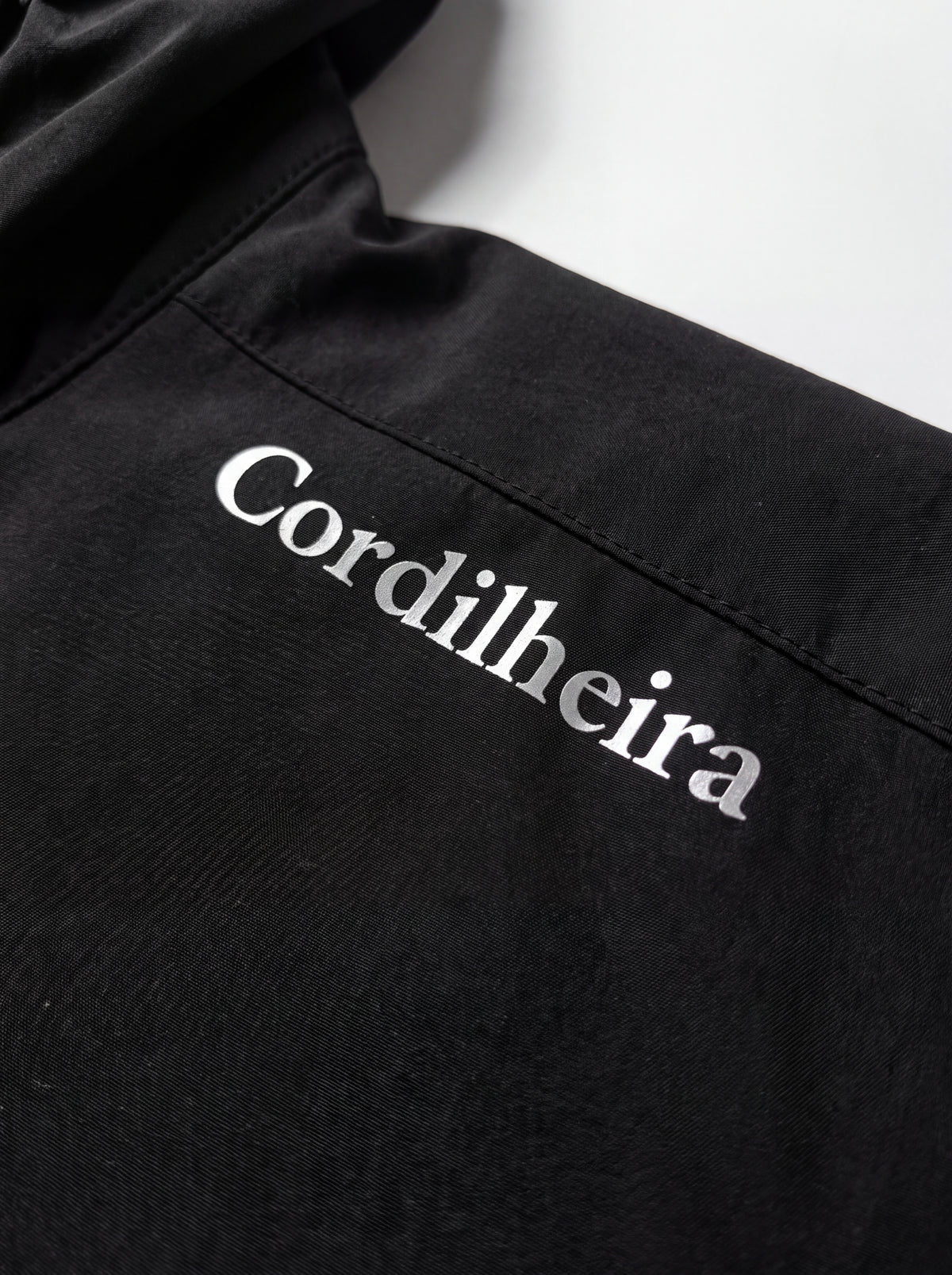 Detalhe macro do logotipo do Corta-Vento Cordilheira Whisper Impermeável UV40+, Roupa da Marca Cordilheira com Boa qualidade e acabamento Confiável.