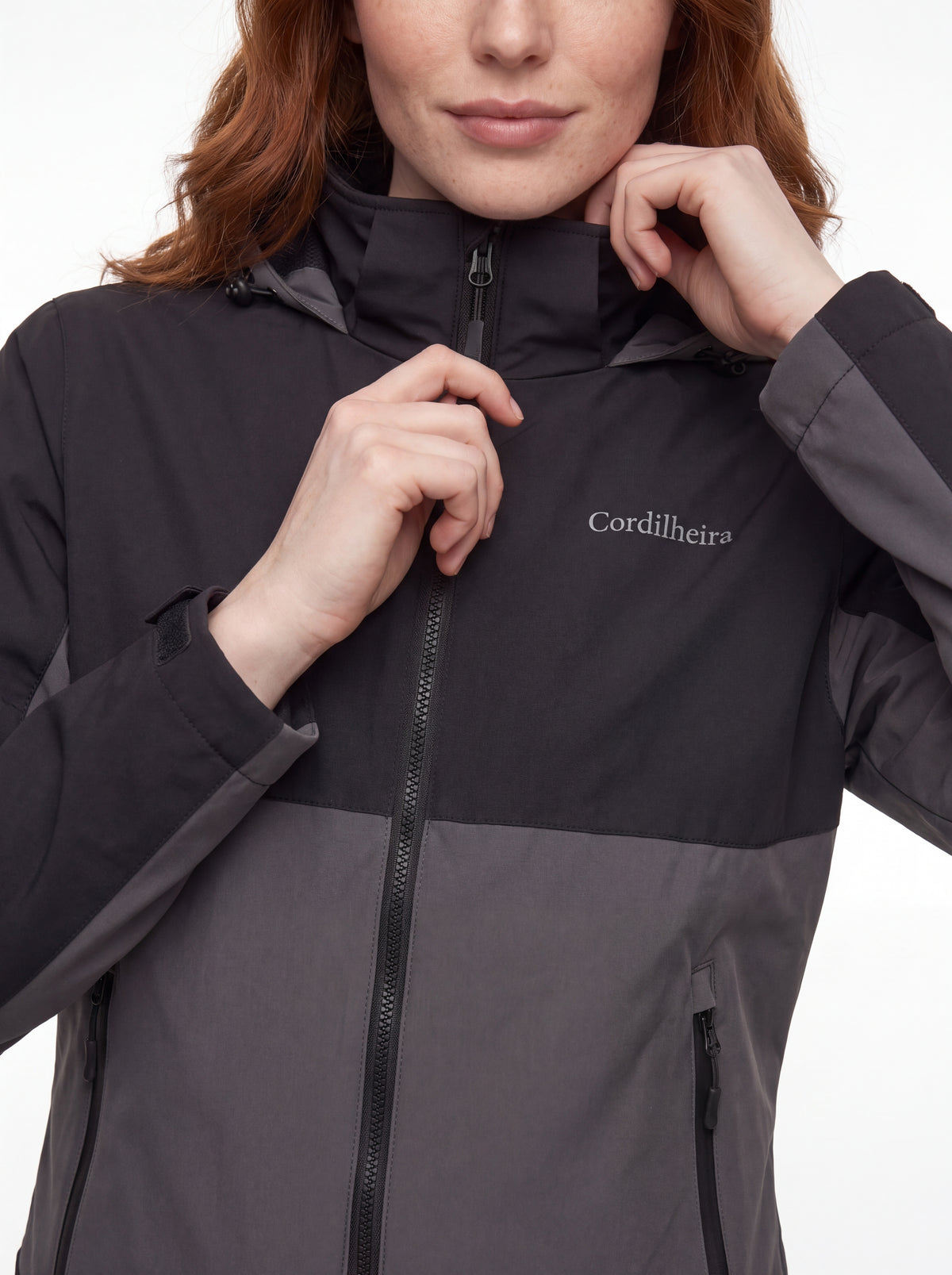 Modelo ajustando a gola da Jaqueta Cordilheira Strategy Feminina Impermeável, Roupa da Marca Cordilheira com Boa proteção e resistência Confiável contra vento e frio.