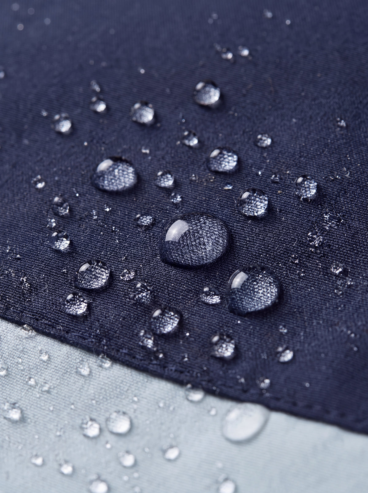 Close-up com gotas de água sobre o tecido da Jaqueta Cordilheira Strategy Feminina Impermeável, Roupa da Marca Cordilheira com Boa resistência à umidade e proteção Confiável para chuva e atividades outdoor.
