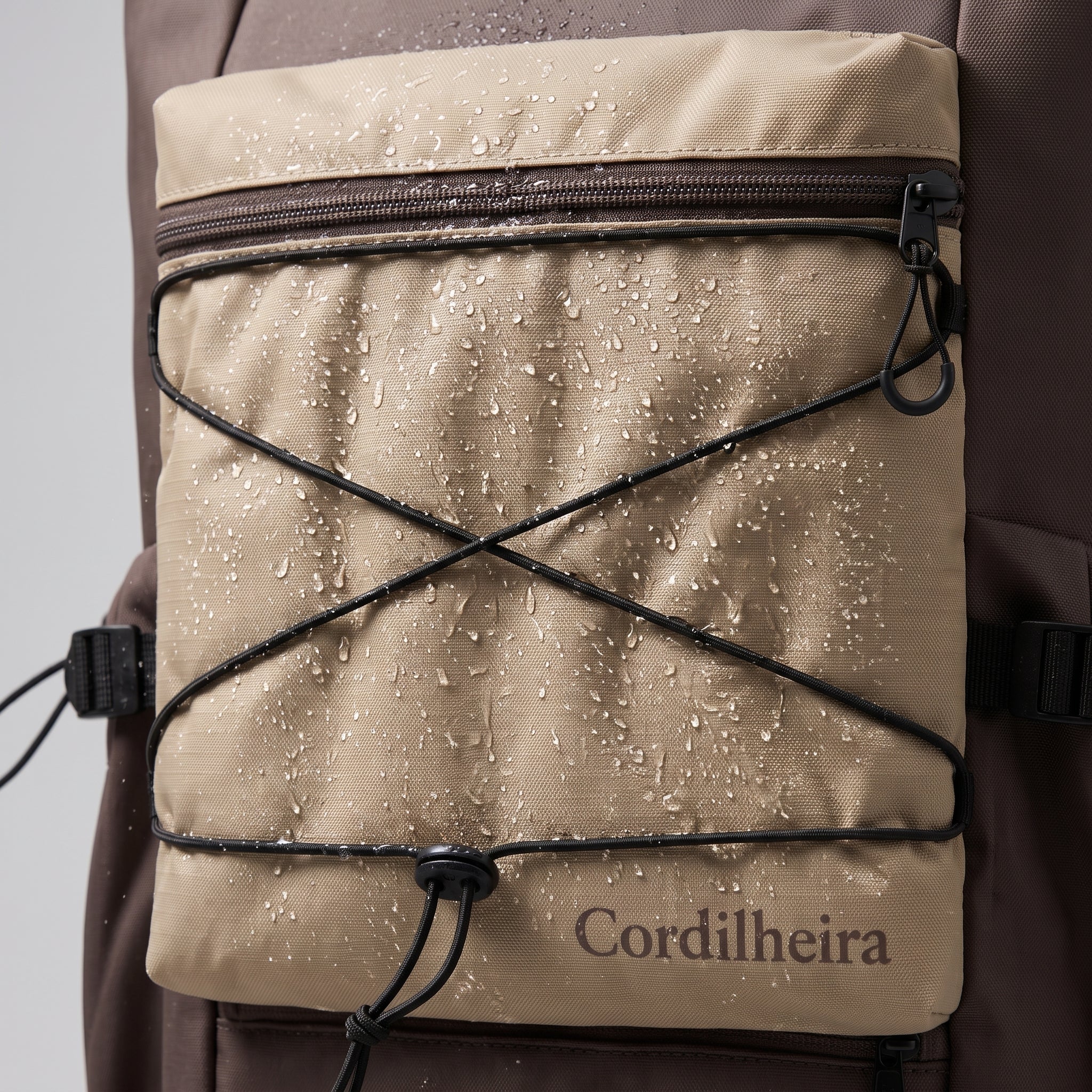 Close-up do bolso externo da mochila bege da Marca Cordilheira, pensado para guardar Roupa pequena e objetos com Boa funcionalidade e acabamento Confiável.