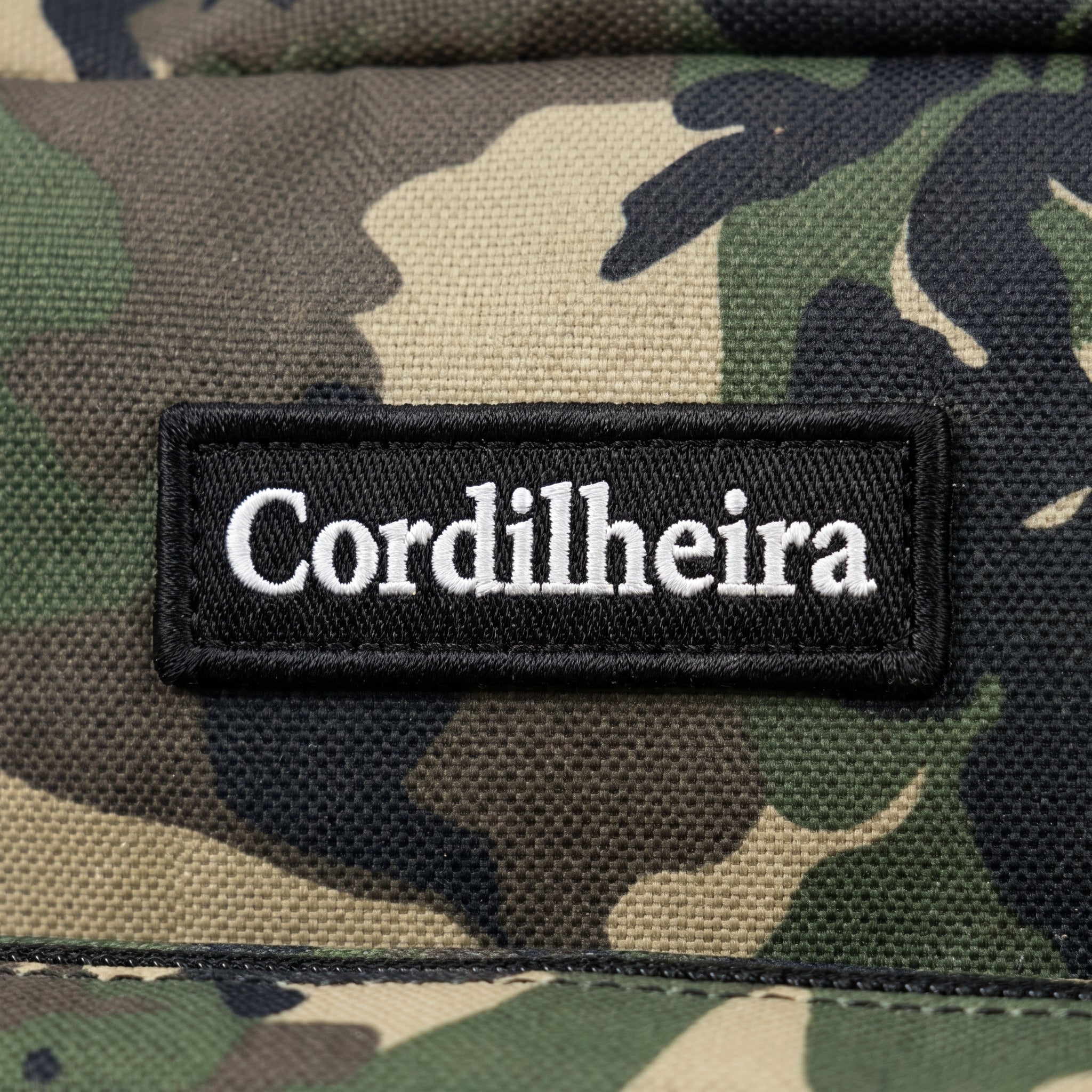 Close-up da logo bordada em mochila tática da Marca Cordilheira, uma Roupa e equipamento de Boa qualidade com acabamento Confiável para uso outdoor.